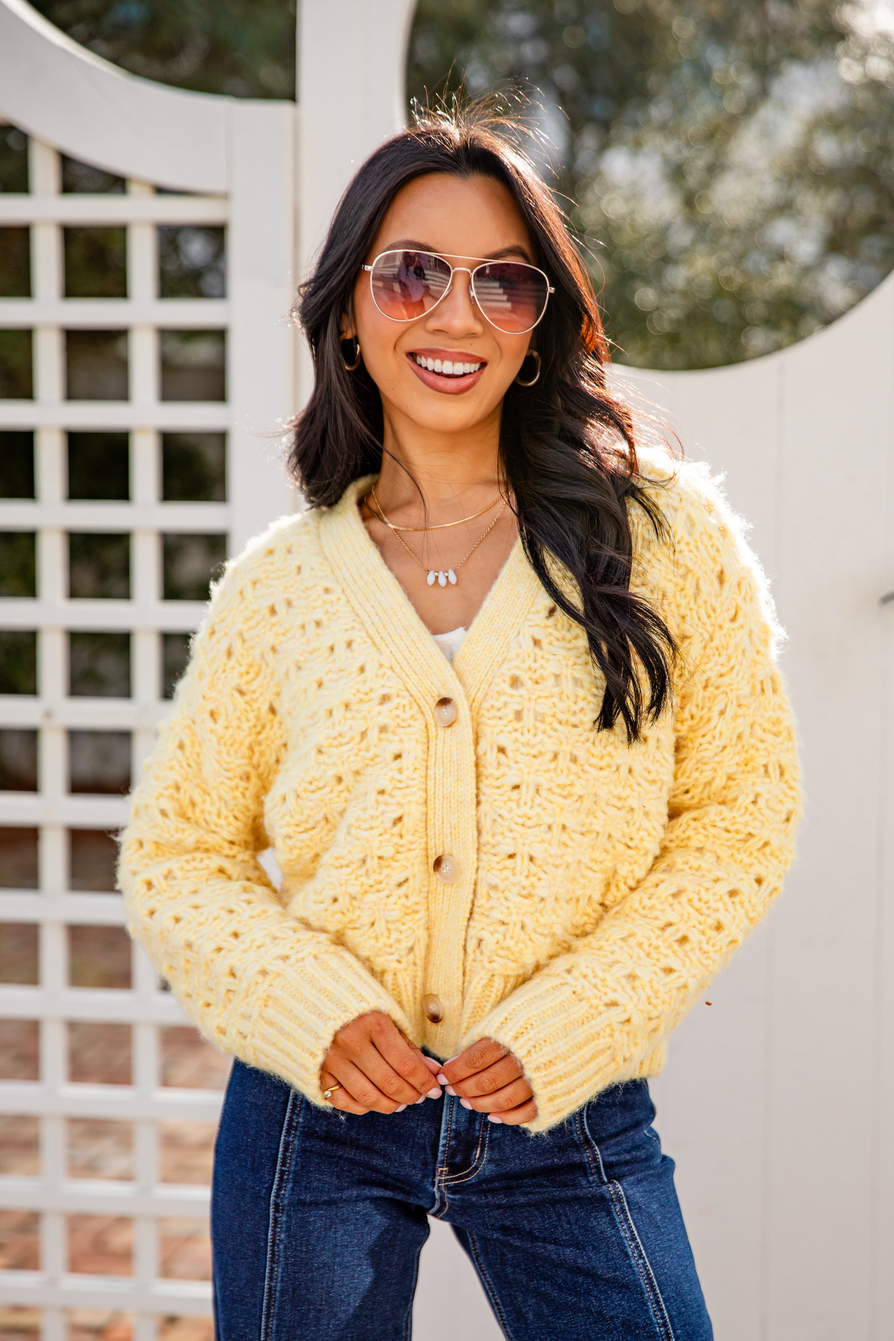 Woman wearing a yellow cardigan and sunglasses outdoors