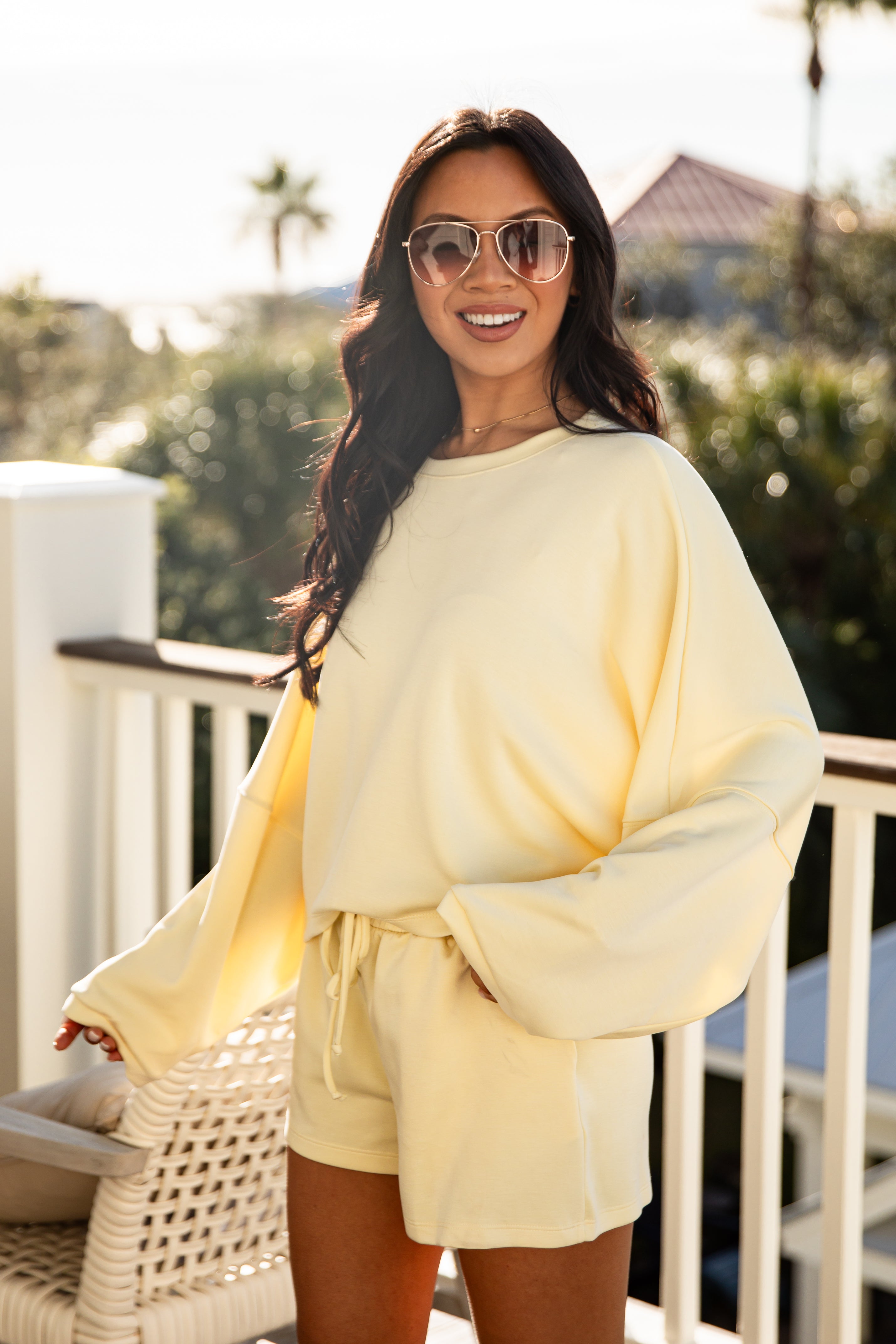 Woman wearing a yellow outfit on a balcony with blurred background