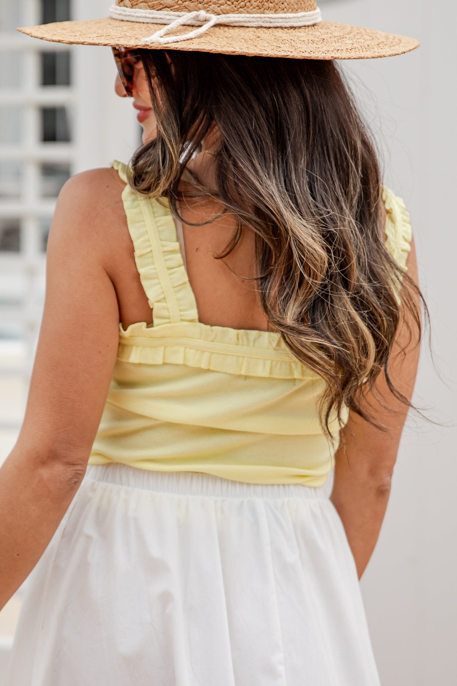 Woman wearing a straw hat and yellow top with a blurred background