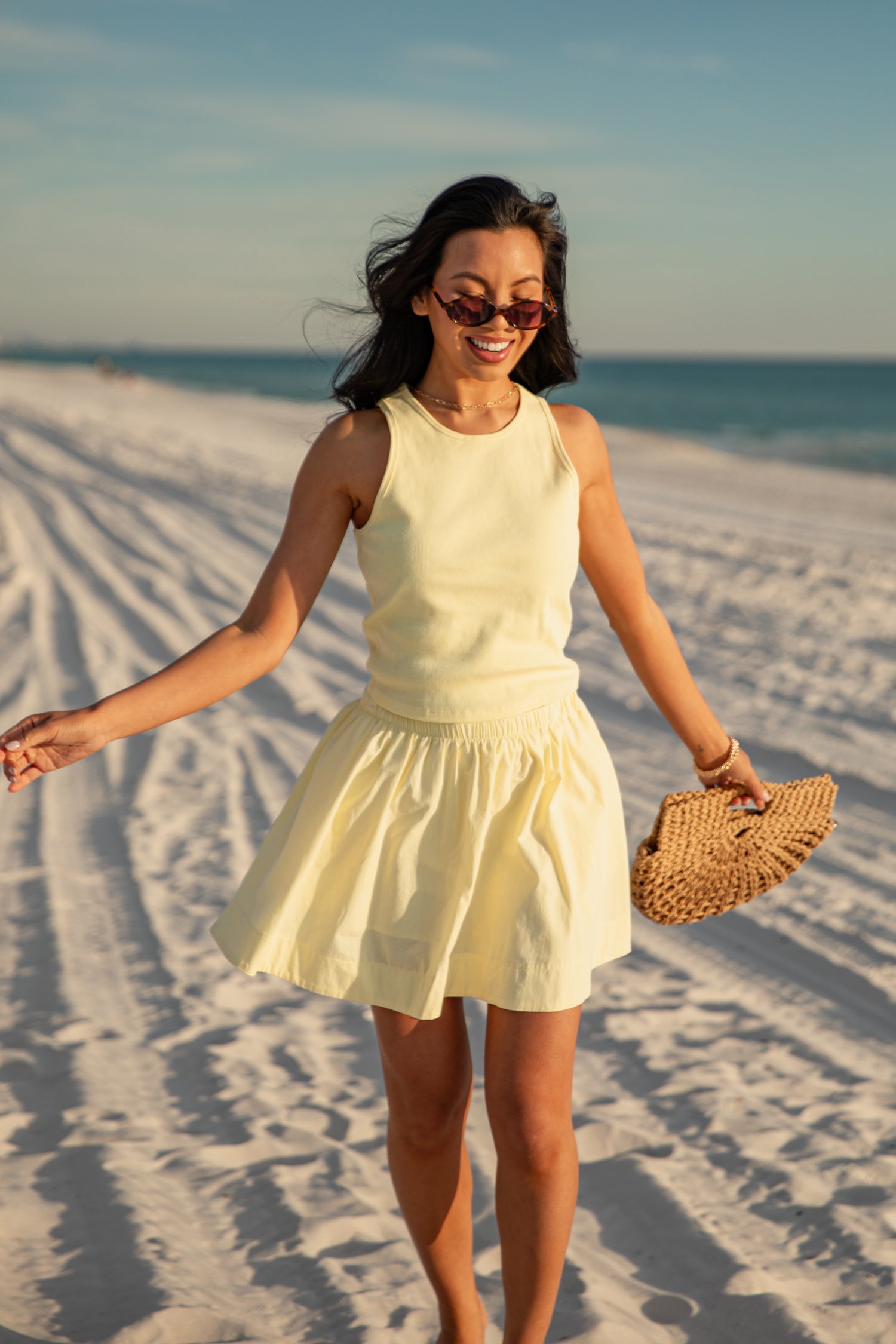 Woman in a yellow dress standing on a sandy beach with ocean view