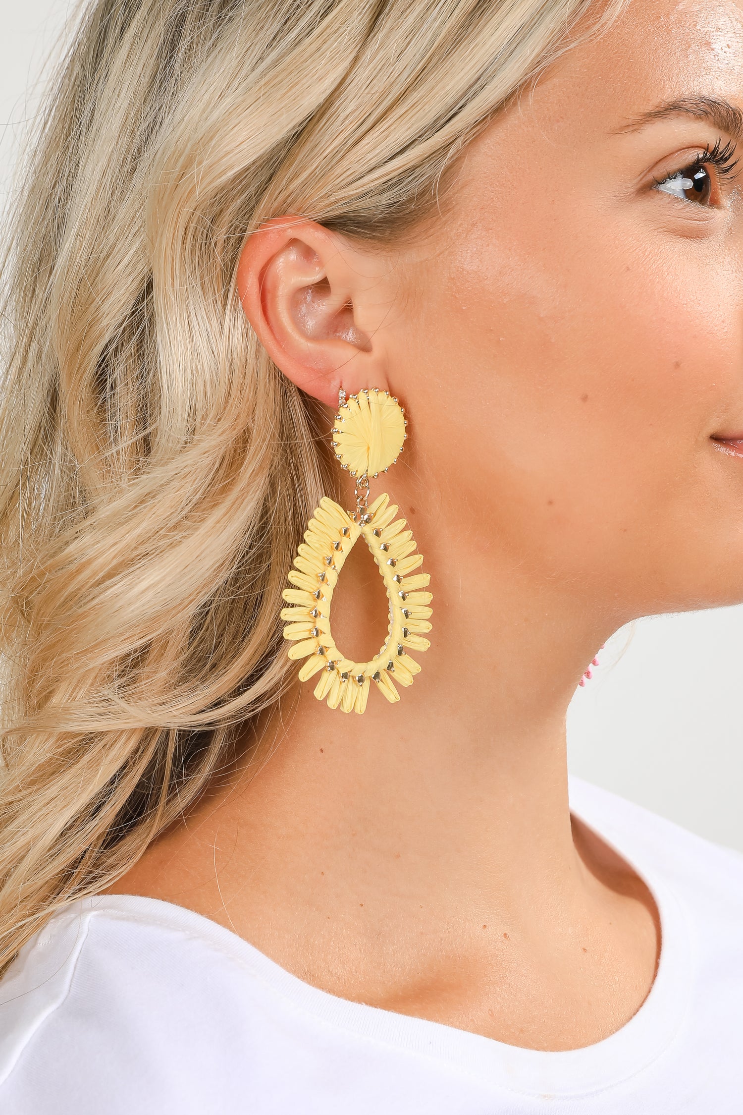 Woman wearing yellow earrings with a plain background