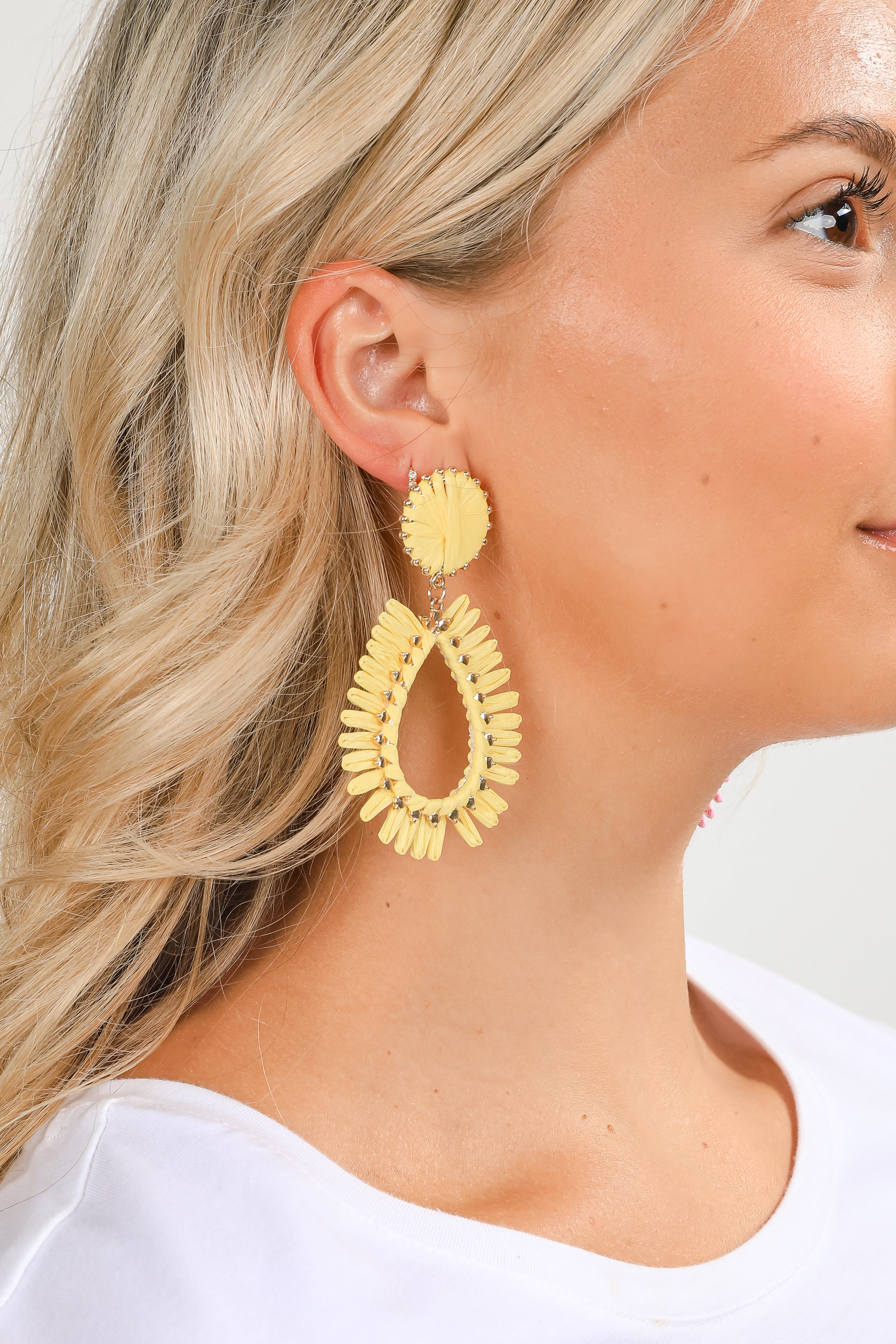 Woman wearing yellow earrings with a plain background
