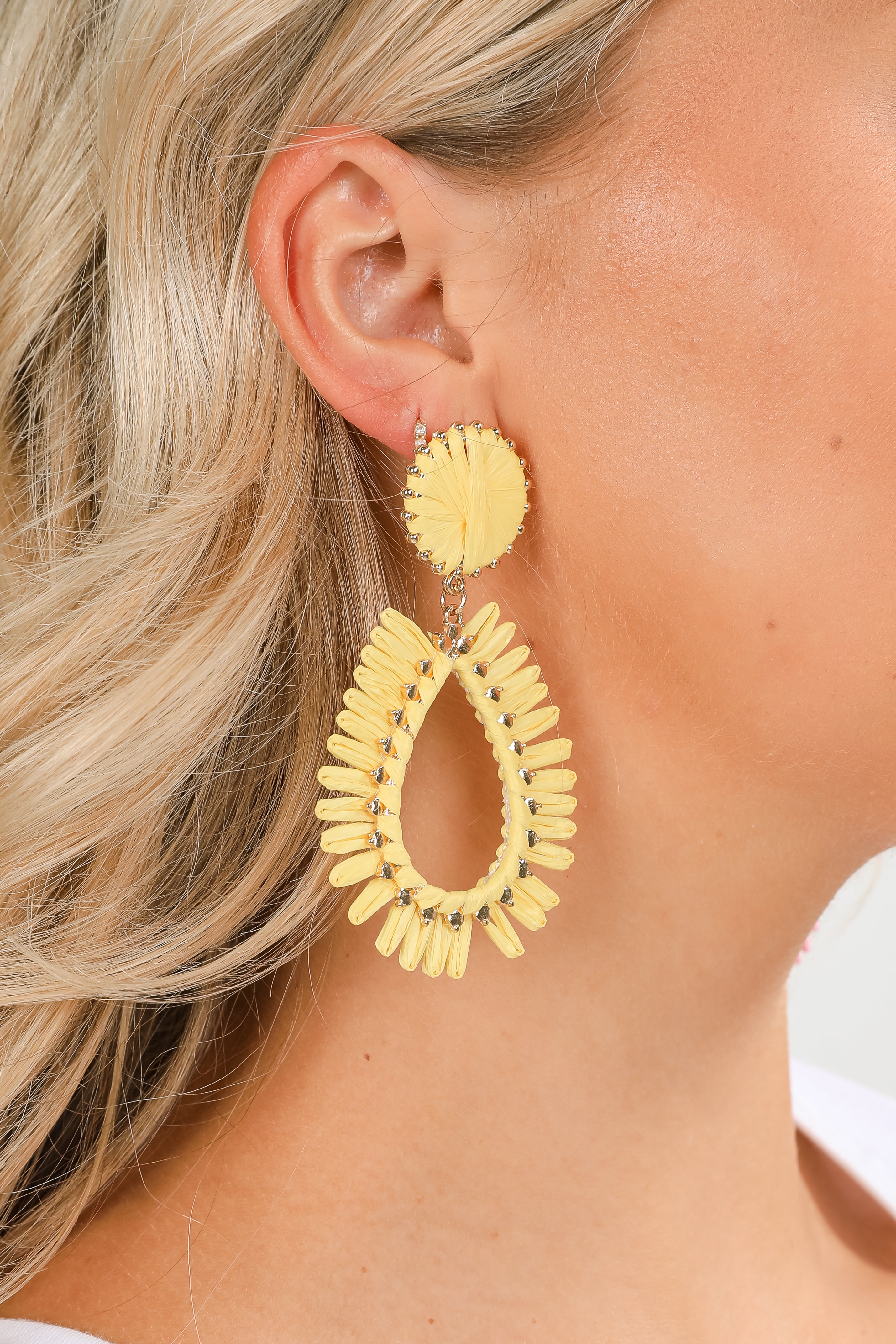 Close-up of a person wearing yellow hoop earrings with a blurred background