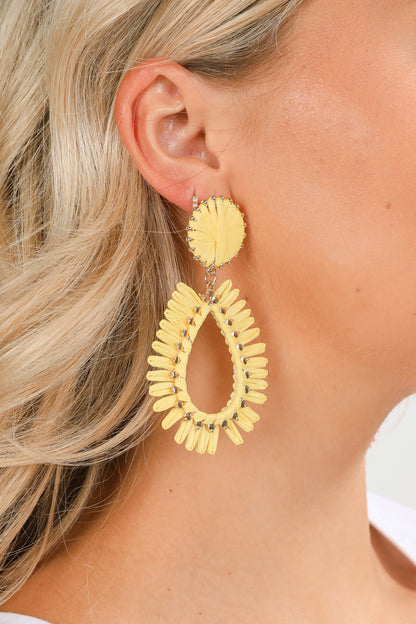 Close-up of a person wearing yellow hoop earrings with a blurred background