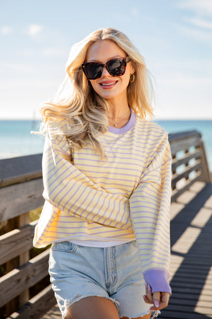 Woman wearing a striped shirt and sunglasses on a wooden pier with ocean view