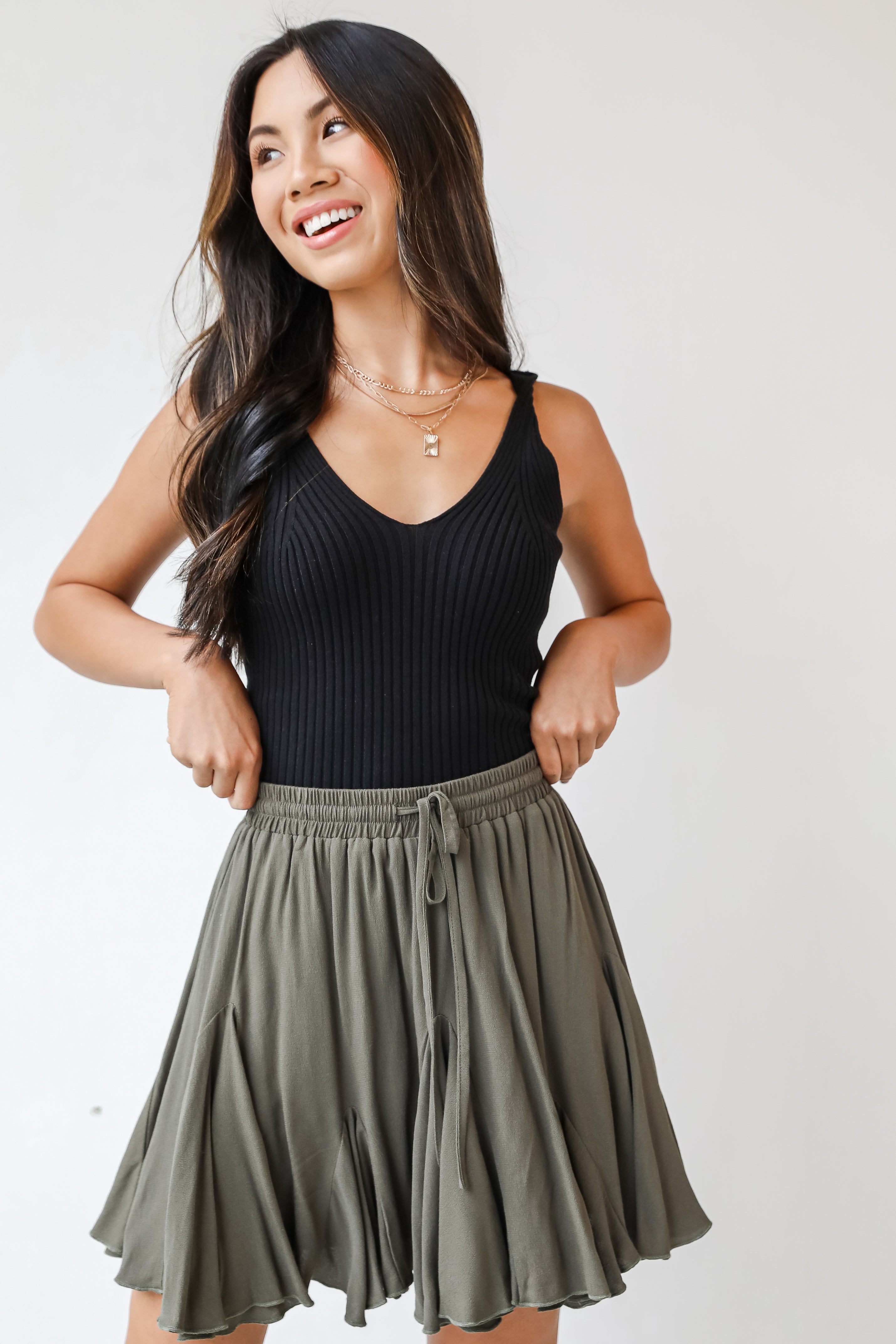 This cute skirt is designed with a lightweight woven knit. It features an elastic waistband with a functional drawstring and a flowy fit that ends at a mini length.