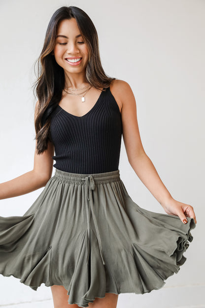 This cute skirt is designed with a lightweight woven knit. It features an elastic waistband with a functional drawstring and a flowy fit that ends at a mini length.